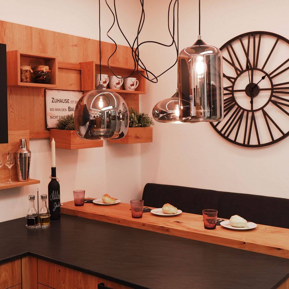 Moderne Küche mit s.luce Cruet Pendelleuchten und stilvollem Holzregal, rustikales Ambiente und einzigartiges Design.
