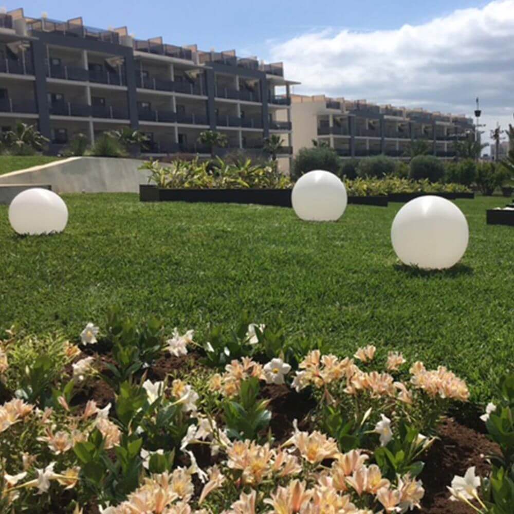 s.luce Globe Set Garten Kugelleuchten auf grünem Rasen im Garten mit Blumenbeet im Vordergrund