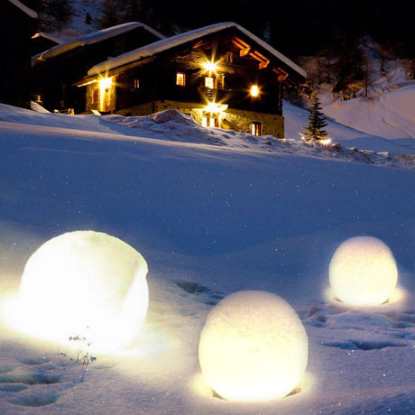 s.luce Globe Set Garten Kugelleuchten leuchten im Schnee vor einem gemütlichen Chalet.