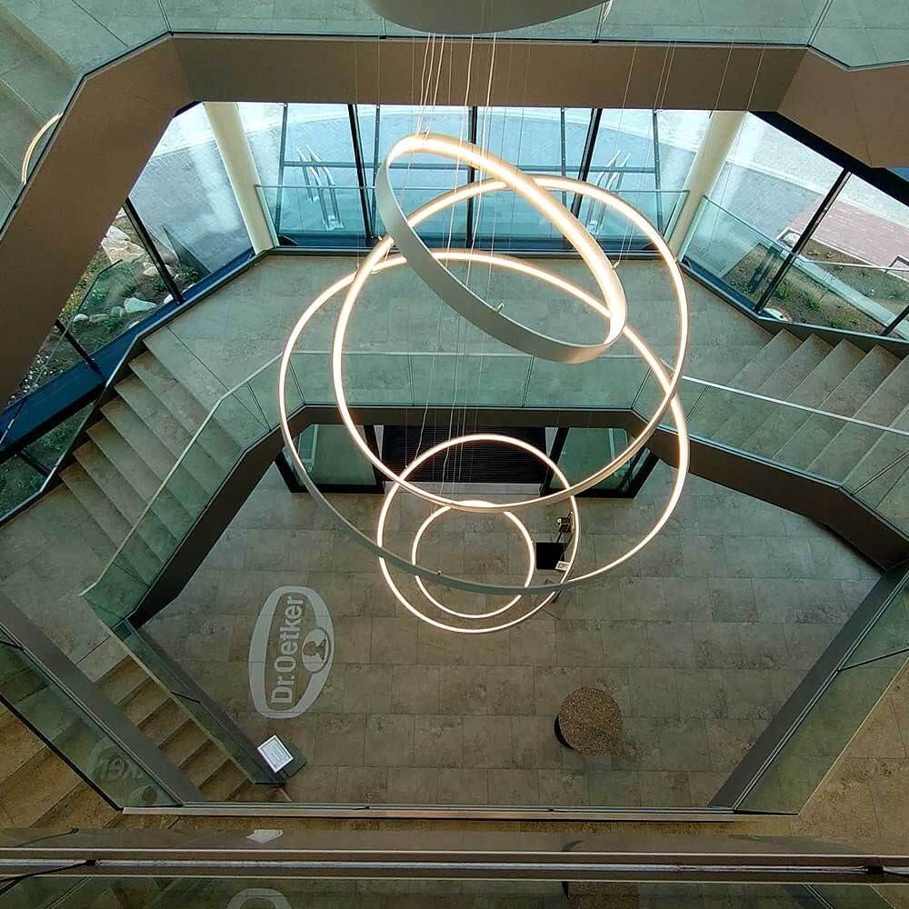 Pendelleuchte aus s.luce Made mit mehreren Ringen, zentrisch aufgehängt in modernem Treppenhaus.