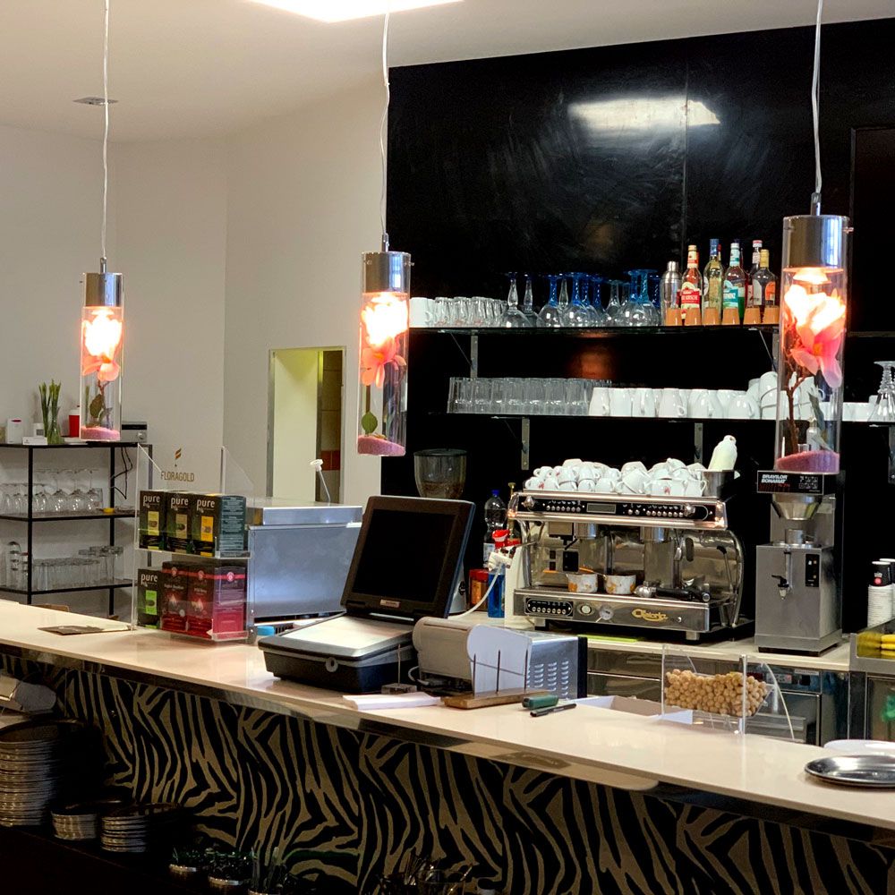 s.luce MyLight Hängeleuchte in einem modernen Café, dekoriert mit bunten Objekten im Glaszylinder
