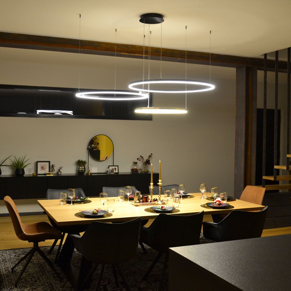 s.luce Lampada a sospensione LED a forma di anello Ø 120 cm sopra un elegante tavolo da pranzo in un soggiorno moderno.