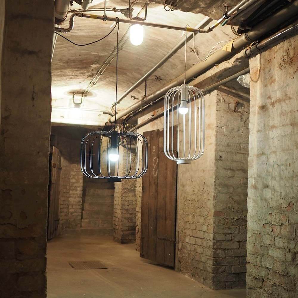 s.luce Rooms M direkt & indirekte Gitter-Pendelleuchte Ø30cm in einem modernen Raum mit Betonwänden.