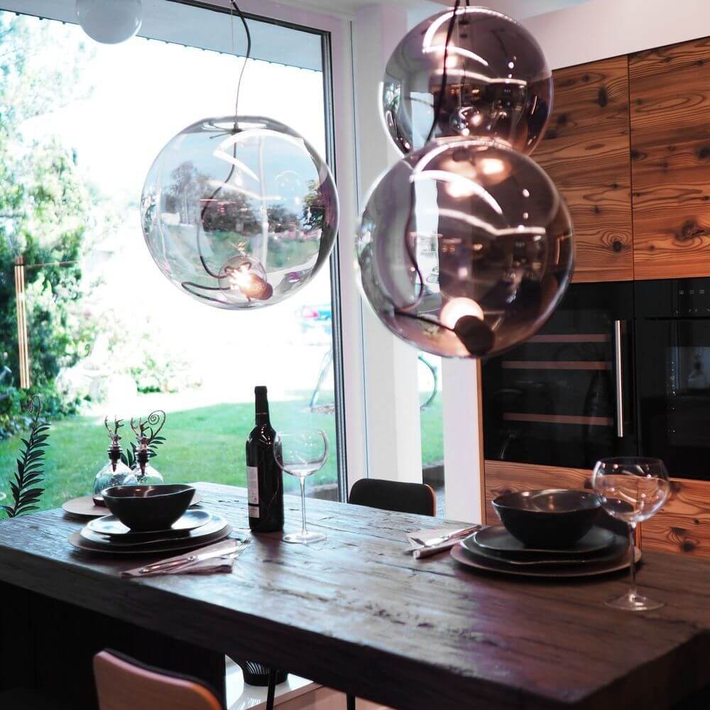 Sphere Galerieleuchte in elegantem Wohnbereich mit Glaskugeln über einem Esstisch, für stimmungsvolle Beleuchtung.