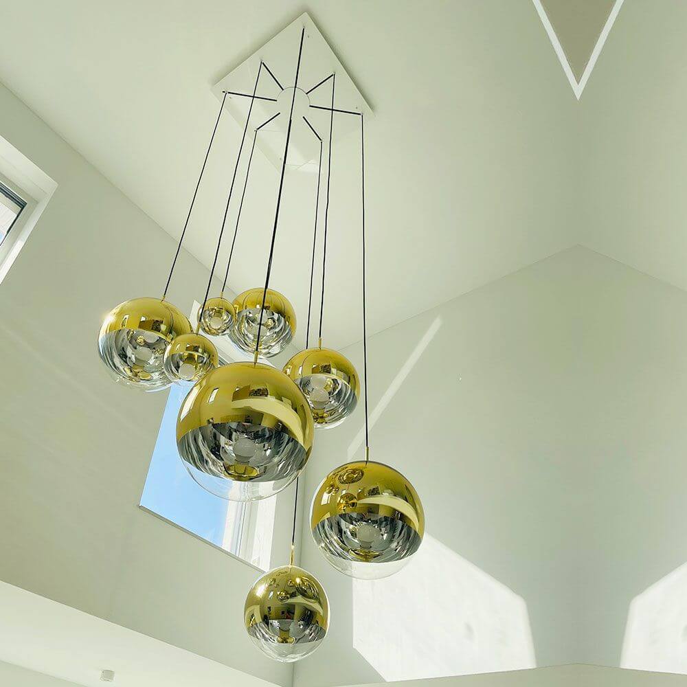 Hängelampe mit goldenen und glänzenden Kugeln in modernem Wohnraum.