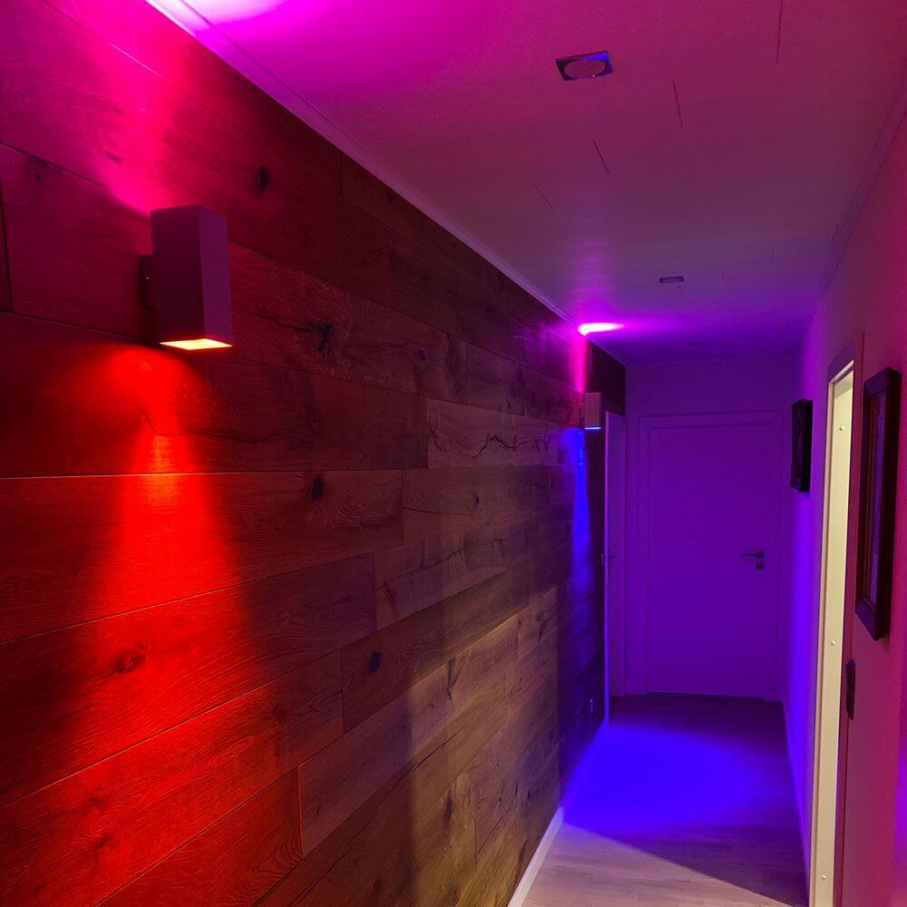 Beleuchteter Flur mit RGBW GU10 LED Leuchten in verschiedenen Farben, Holzvertäfelung im Hintergrund.