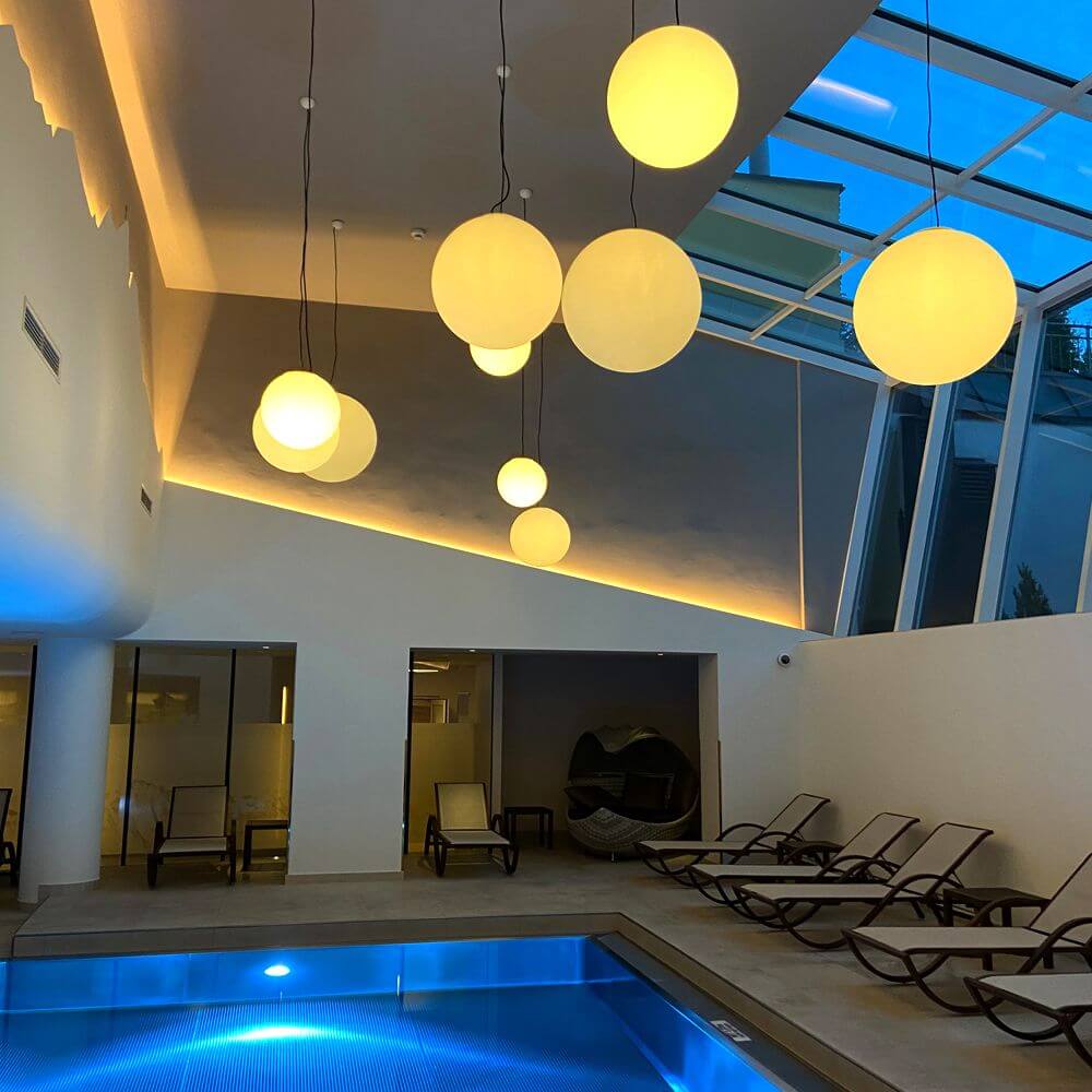 s.luce Globe Hänge-Kugellampe für Innen & Außen IP54 in stilvollem Innenbereich über einem Pool.