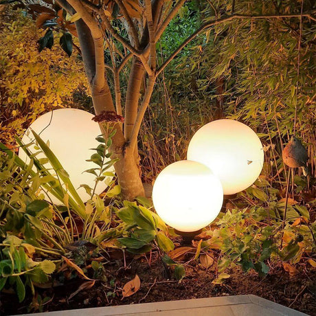 s.luce Set di globi da giardino in un giardino con piante e luce d'atmosfera.