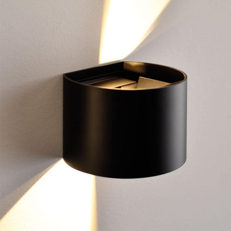 Nowoczesna lampa ścienna Ixa w czerni z zaokrągloną osłoną, idealna do stylowego aranżowania wnętrz.