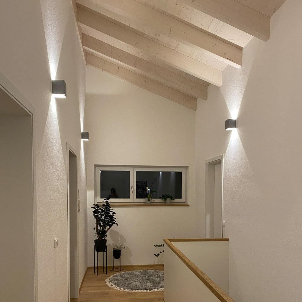 s.luce Ixa LED High Power Wandlampe IP20 in modernem Flur mit Holzdecke und dekorativem Licht.