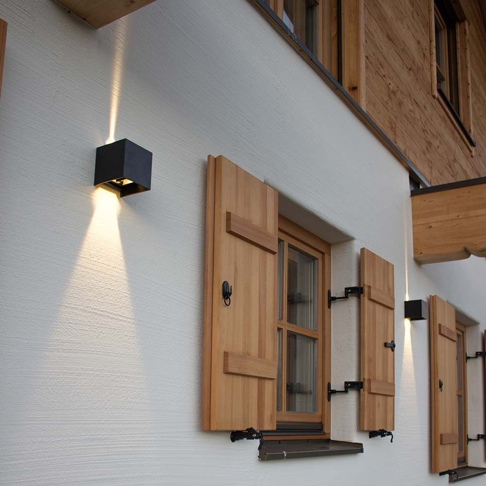 s.luce Ixa LED Wandlampe mit Bewegungsmelder an einer Wand mit Holzfensterläden.