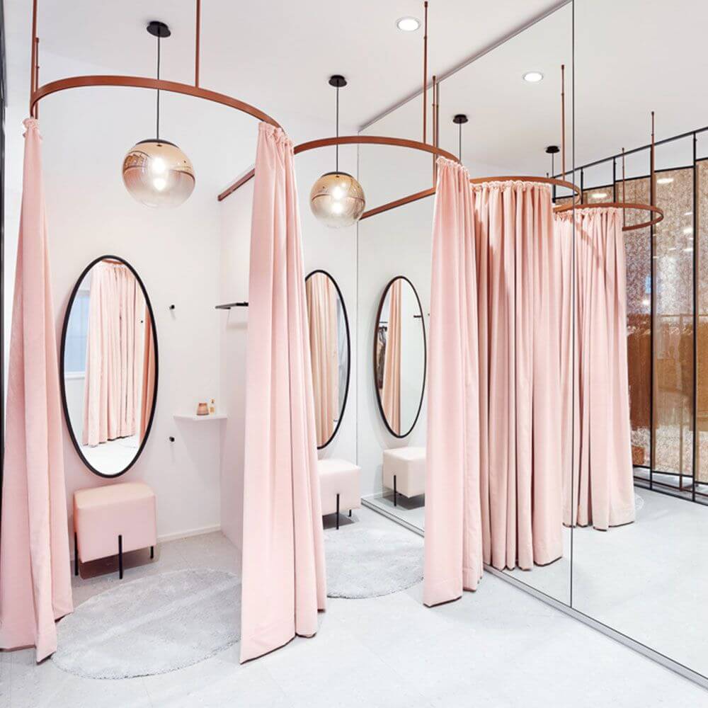 Eleganter Umkleidebereich mit rosa Vorhängen, Spiegeln und modernen Leuchten in einem stilvollen Raum.