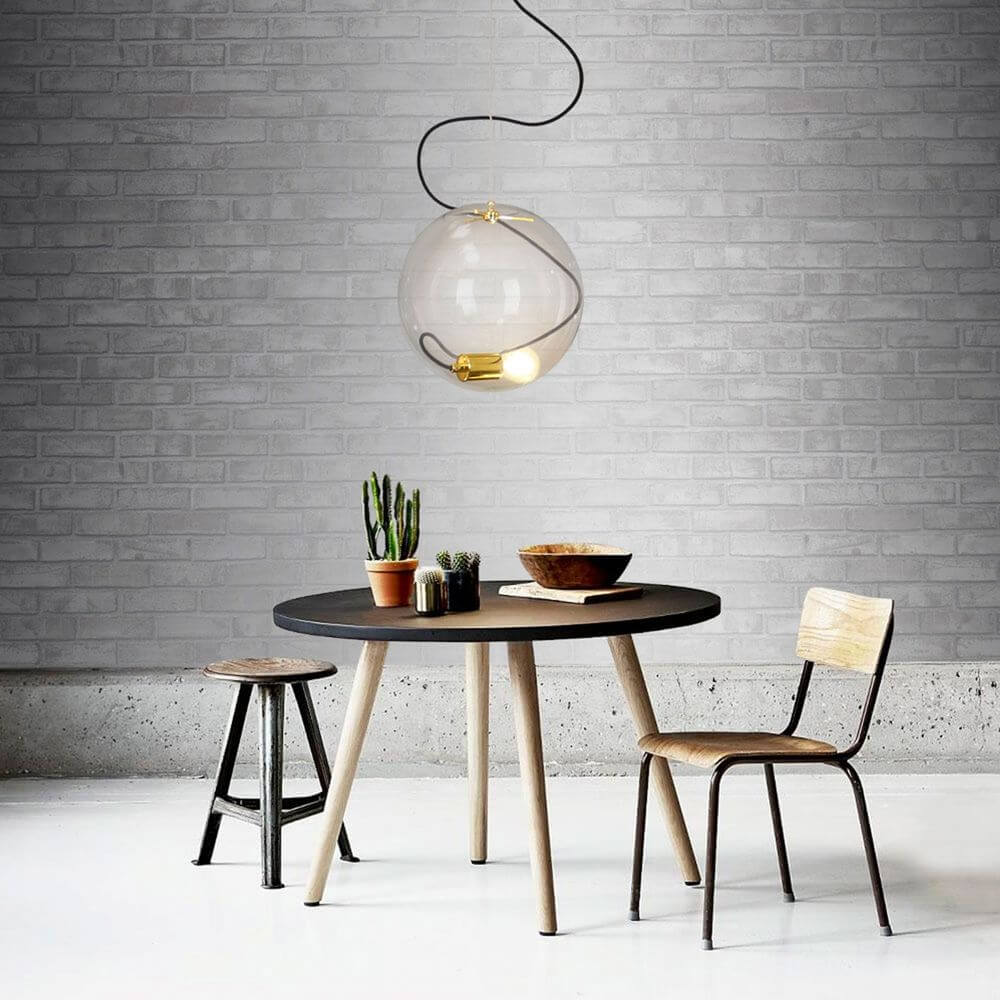 s.luce Sphere Pendelleuchte Glaskugel über einem modernen Esstisch mit Pflanzen und Holzstühlen