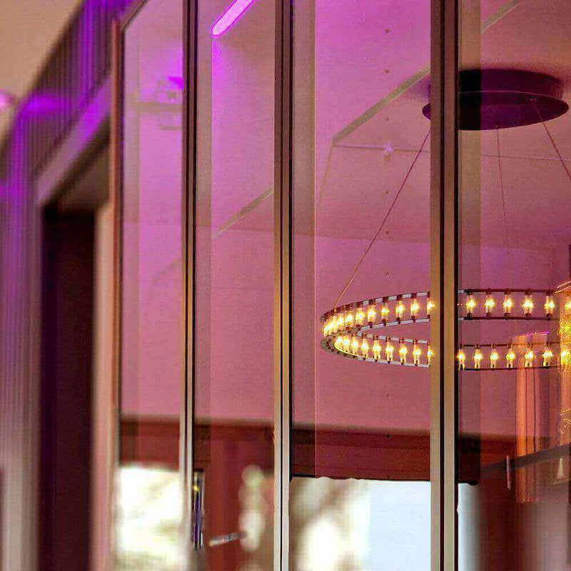 Espejos reflectantes con iluminación púrpura y una moderna lámpara de araña al fondo.