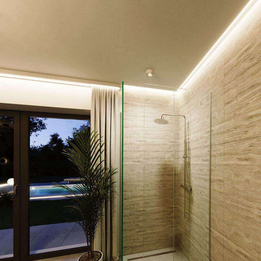 Moderne Dusche mit Glaswänden, sanfter Beleuchtung und Blick auf den Garten mit Pool.