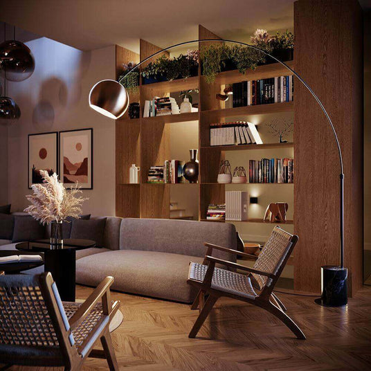 s.luce Lampe arc de design Ball avec pied en marbre moderne dans un salon élégant avec une bibliothèque.