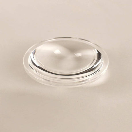 s.luce Beam Glaslinse auf einer neutralen Oberfläche, klar und glänzend, ideal für Lichtreflexion.