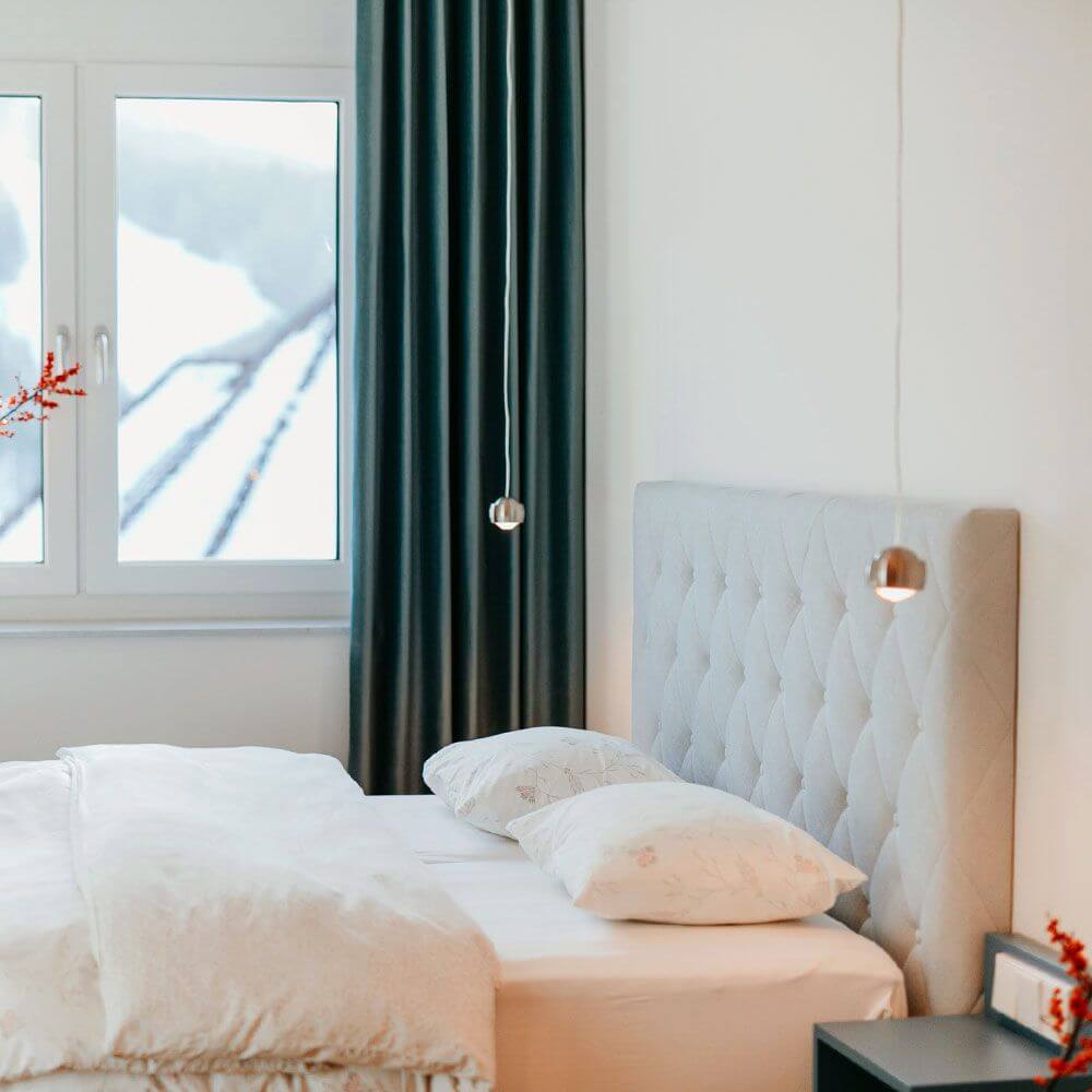 s.luce Beam LED Hängeleuchte Ø 8cm in elegantem Schlafzimmer mit hellem Bett und Vorhängen.