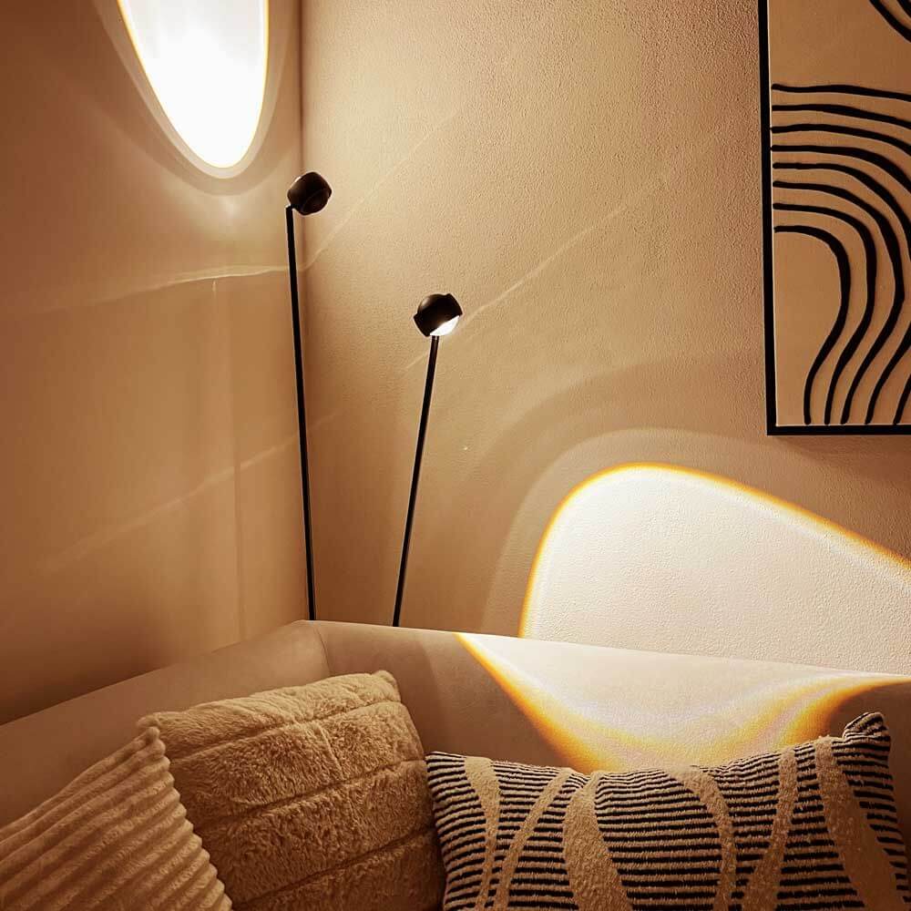 s.luce Beam LED Stehleuchte 2-flammig 145cm Touchdimmer strahlt sanftes Licht über ein Sofa.