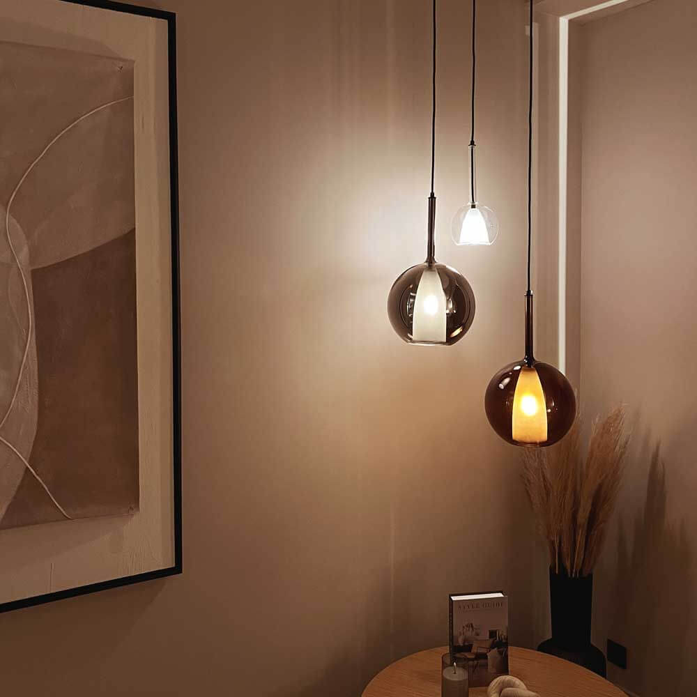 s.luce Belluna Galerieleuchte 3-flammig Ø 40cm Baldachin im modernen Raum mit Kunstwerk und Holzstühlen.