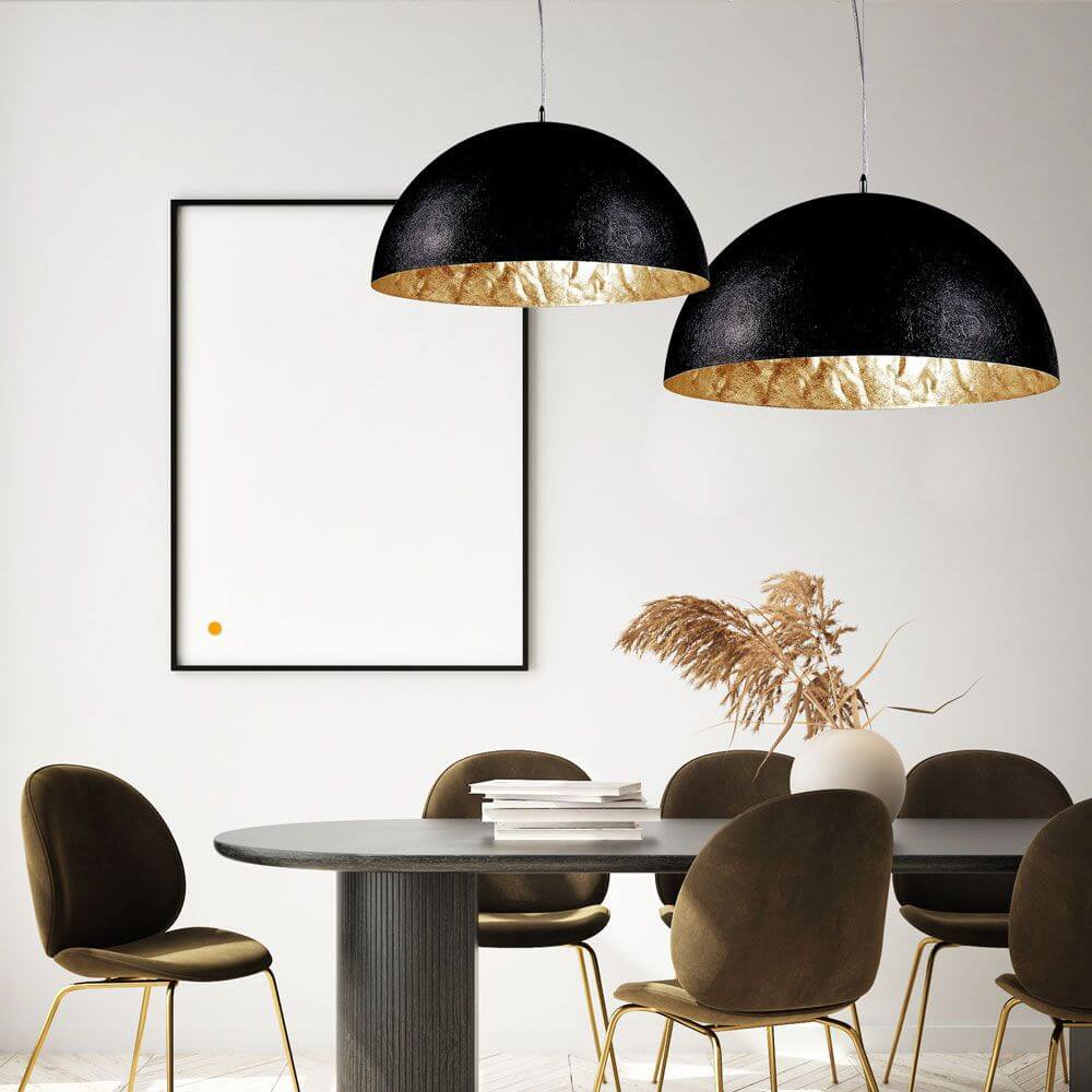 s.luce Blister Pendelleuchte in Schwarz und Gold über einem eleganten Esstisch mit modernen Stühlen.