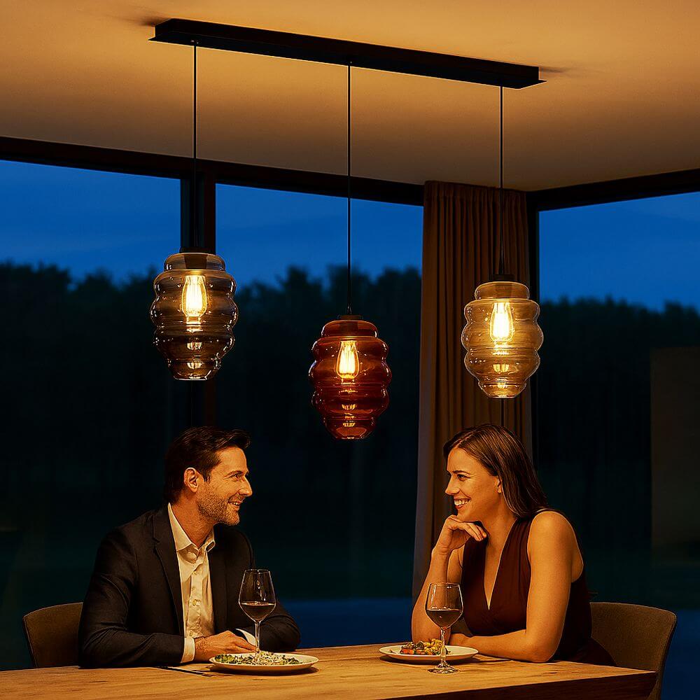 s.luce Echos Esszimmer-Hängeleuchte 3-flammig 120cm Ø 25cm über einem Tisch mit zwei Menschen beim Essen.