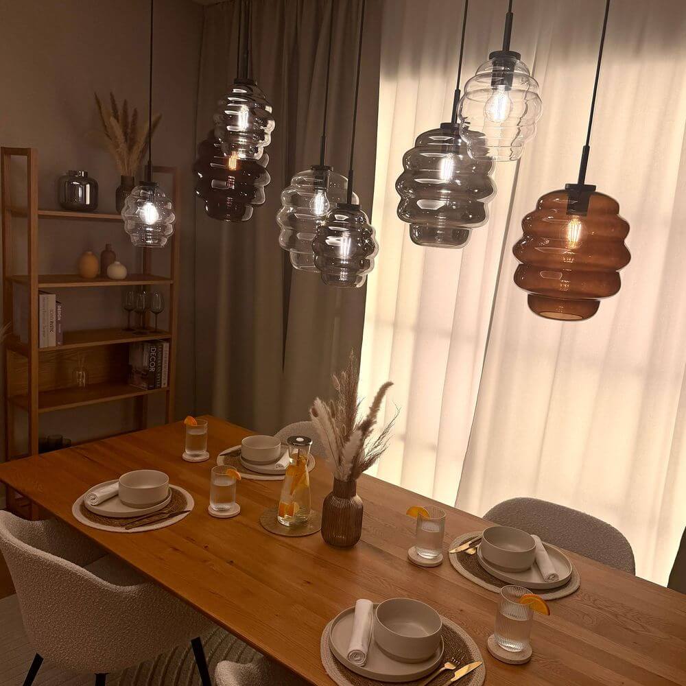 s.luce Echos Esstischlampe 8-flammig 160cm 2-reihig Ø 18cm über modernem Esstisch mit 8 mundgeblasenen Glaskörpern in Cognac, Rauch und Klar