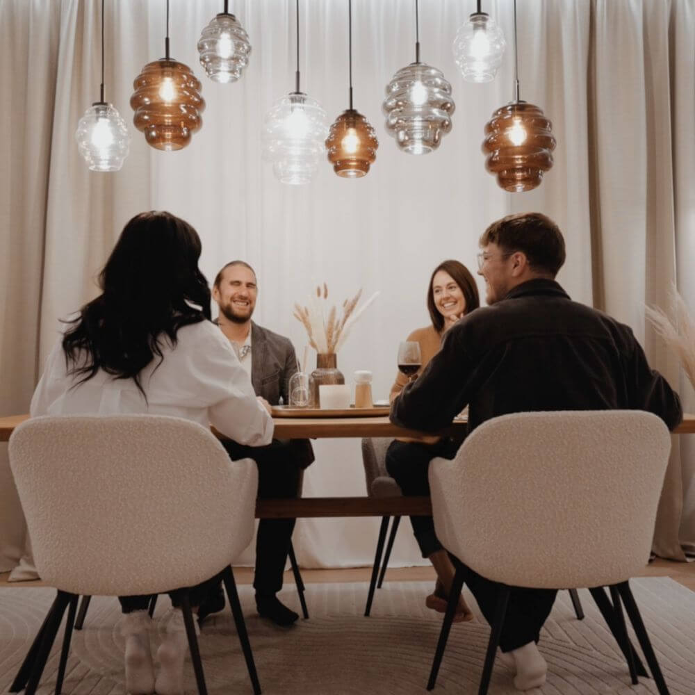 s.luce Echos Esstischlampe 8-flammig 200cm 3-reihig Ø 18/25cm über einem Esstisch mit vier Personen.