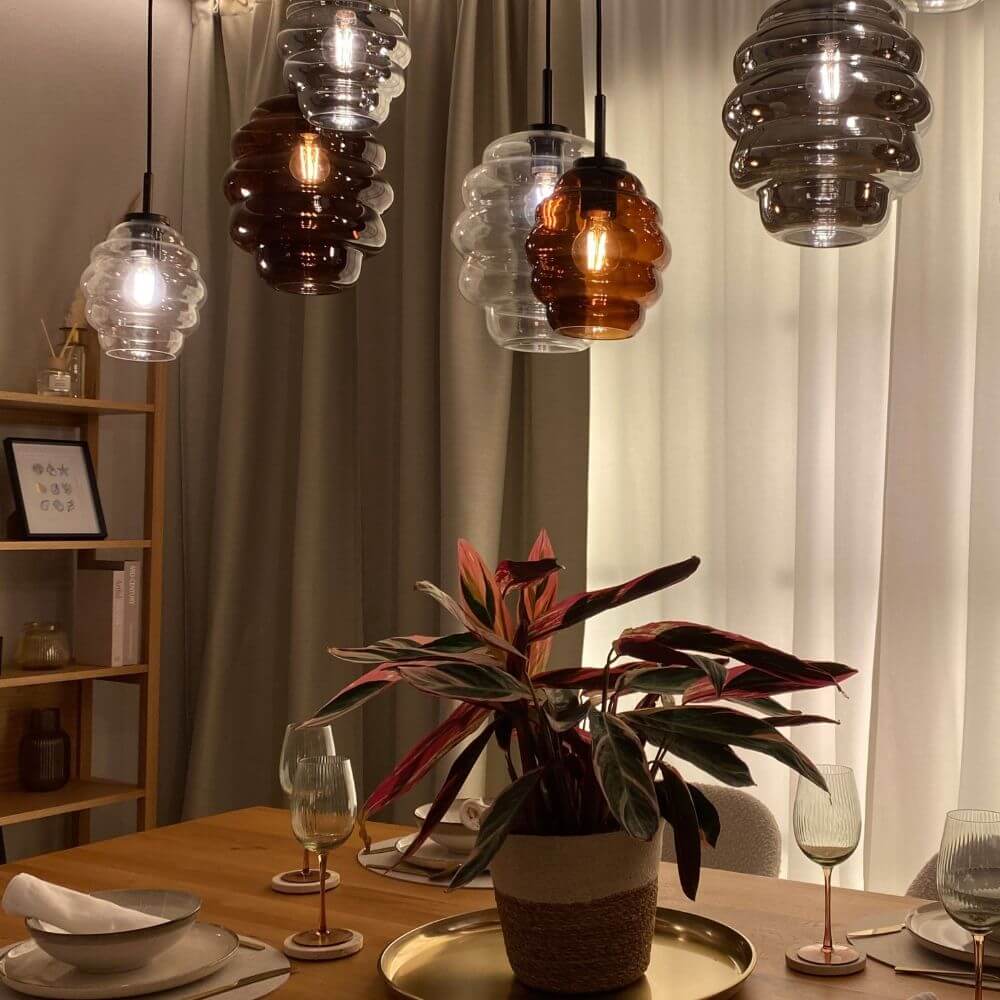 s.luce Echos Esstischlampe 8-flammig 200cm 3-reihig Ø 18/25cm hängend über einem Esstisch mit Pflanzen.