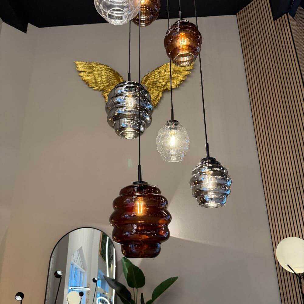 s.luce Echos Glas Galerie-Pendelleuchte Aufhängung 500cm Weiß in einem modernen Raum mit goldenen Flügeln.