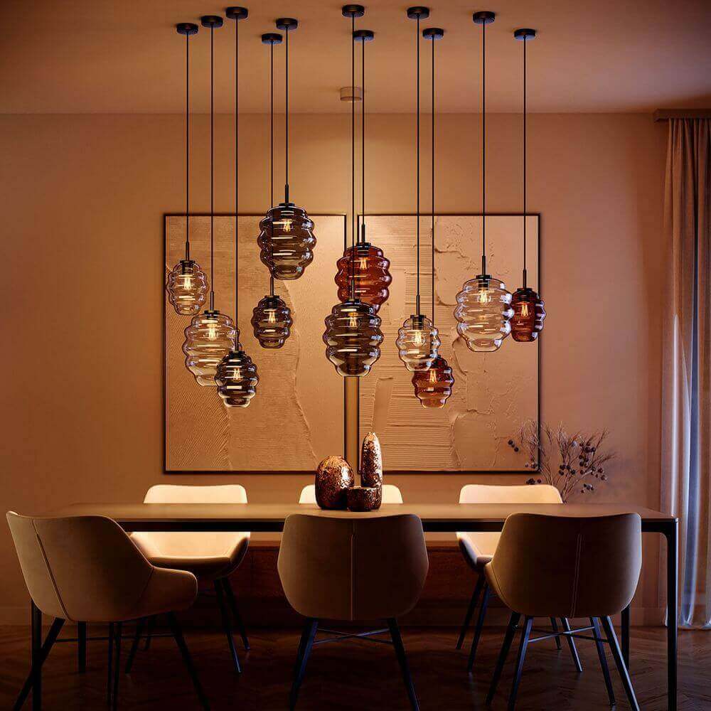 s.luce Echos Glas-Hängelampe in einem eleganten Esszimmer mit warmem Licht und modernen Möbeln.