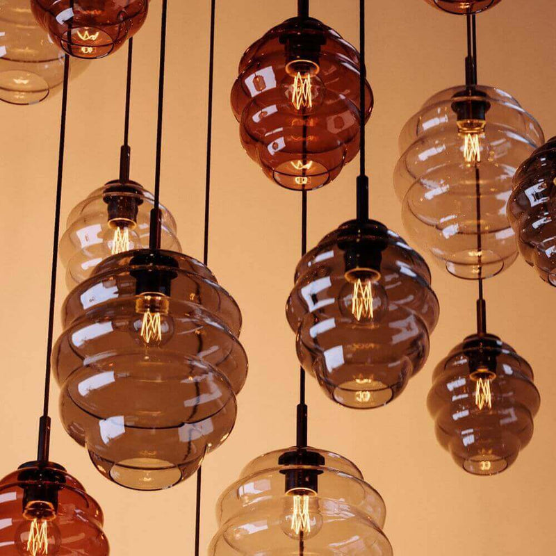 Hängende Glühbirnen-Lampen in verschiedenen transparenten Farben für stilvolle Innenräume.