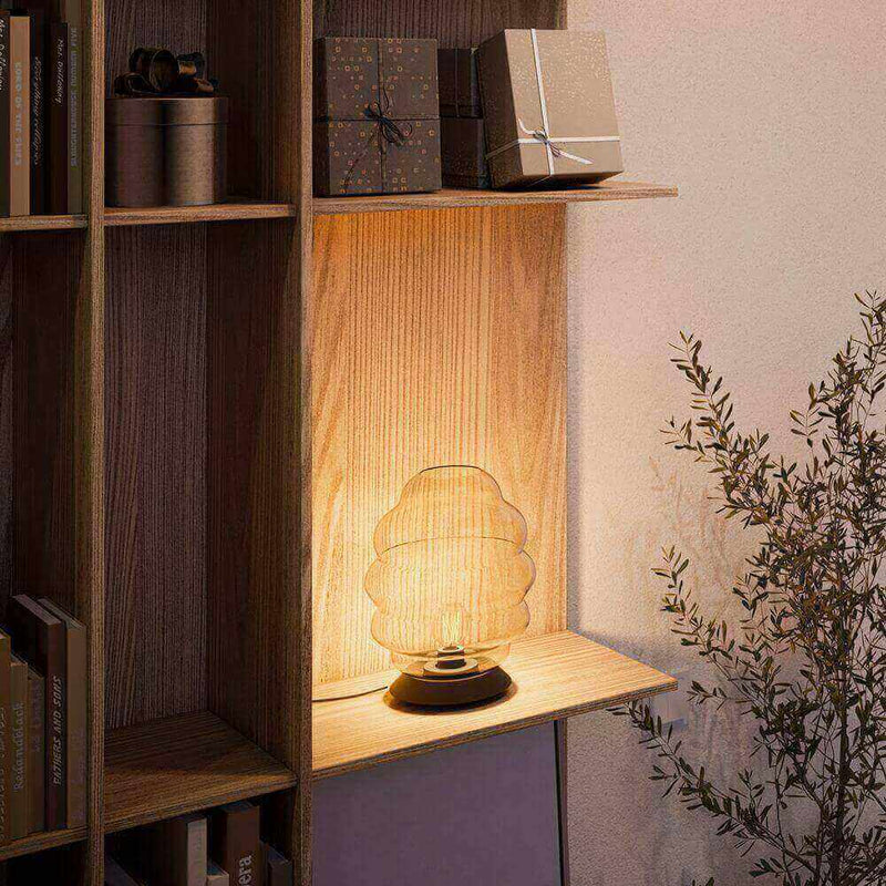 Elegante Lampe auf einem Regalsystem, umgeben von Geschenken und Pflanzen, schafft gemütliche Atmosphäre.