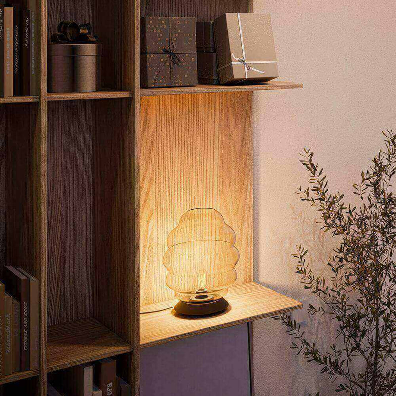 Elegante Lampe auf einem Regalsystem, umgeben von Geschenken und Pflanzen, schafft gemütliche Atmosphäre.
