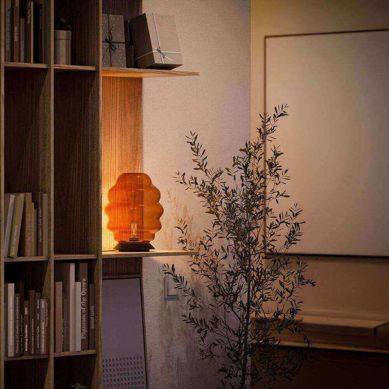 Gemütliche Wohnatmosphäre mit einem orangefarbenen Tischlampe und Pflanzen in einem modernen Raum.