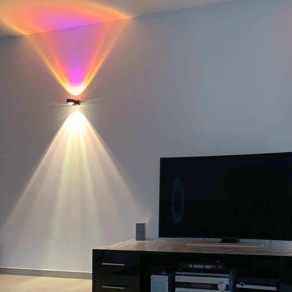 s.luce Beam Glas Farbfilter erzeugt farbige Lichtakzente an der Wand neben einem Fernseher.