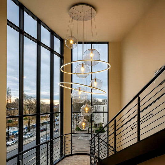 Moderne Hängeleuchte in Treppenhaus mit großen Glaskugeln und elegantem Design, umgeben von großen Fenstern.