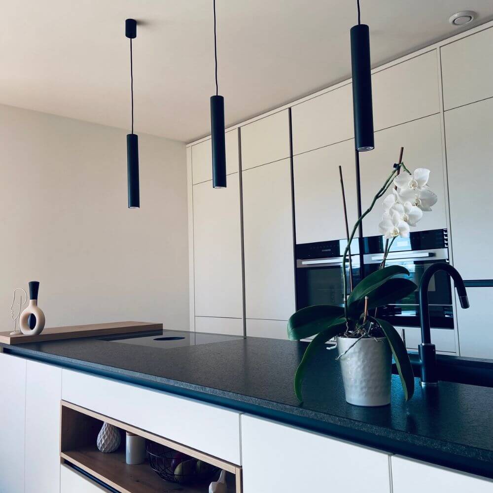 s.luce Lampada a sospensione moderna Crutch a forma di cilindro sopra una cucina moderna con orchidea.