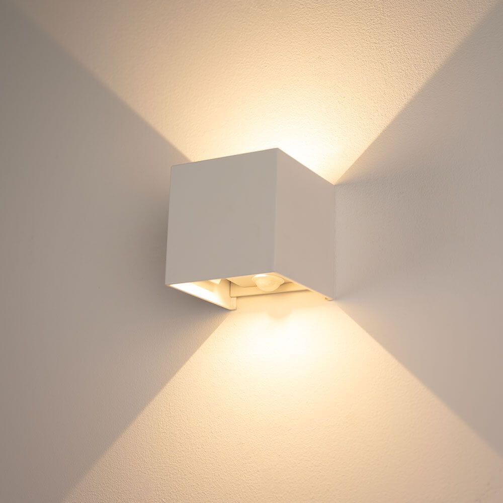 s.luce Ixa LED Wandlampe mit Bewegungsmelder an einer Wand, strahlt warmes Licht aus.