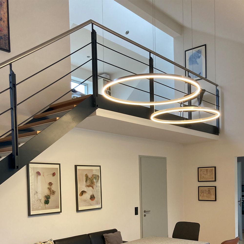 s.luce LED Suspension Ring à 2 lampes excentrée dans un salon moderne au-dessus de la table à manger.
