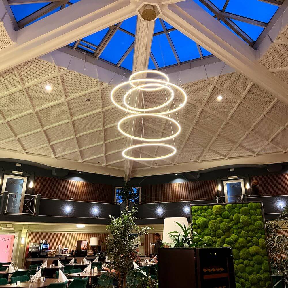 s.luce LED Ring Pendelleuchte 5-flammig Zentrisch in einem modernen Restaurant mit Glasdach.