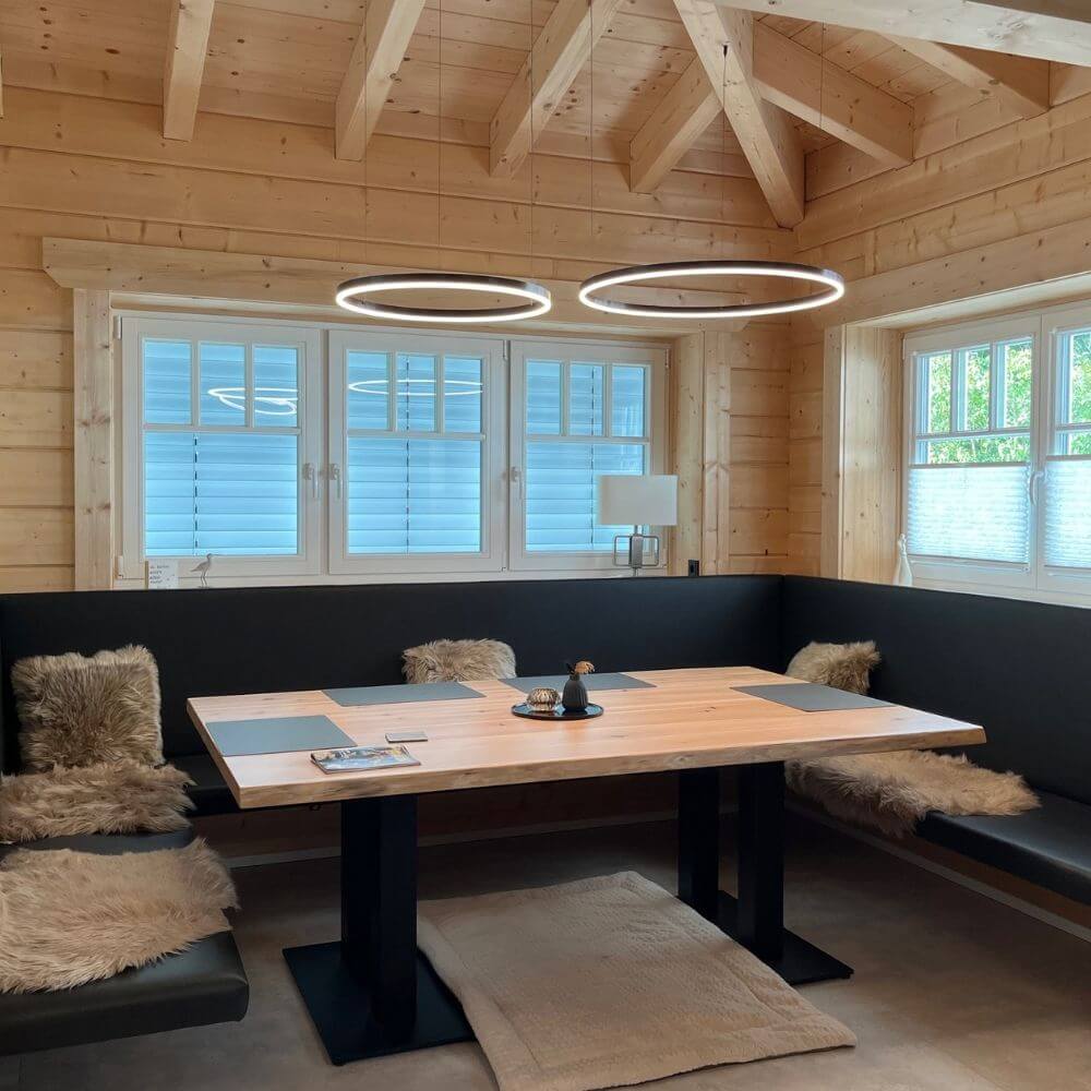 Modern s.luce Ring Hänglampa över en matsal i ett trähus, med minimalistiska designelement.