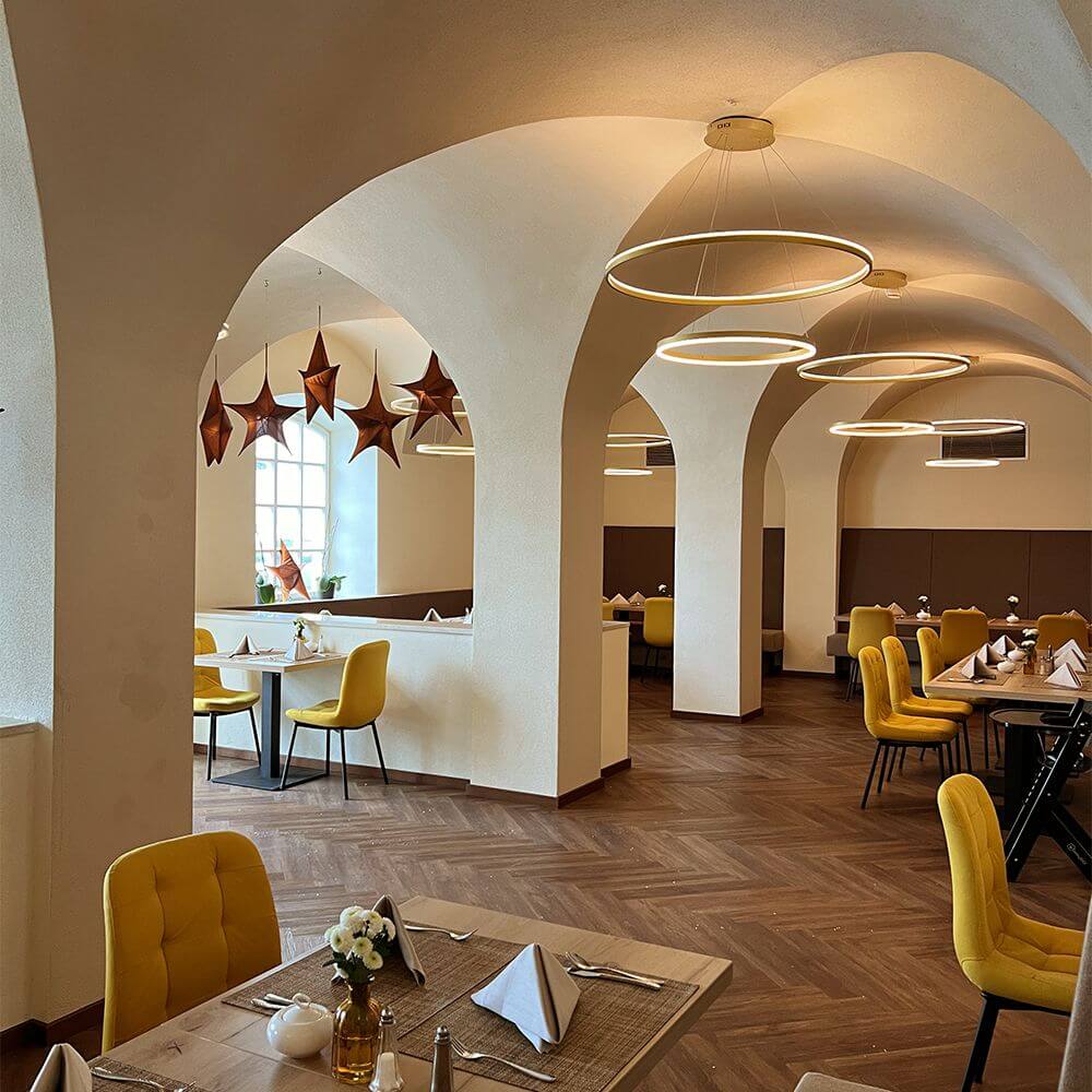 s.luce LED Ring Pendelleuchte rund Direkt oder Indirekt in modernem Restaurant mit eleganten gelben Stühlen.