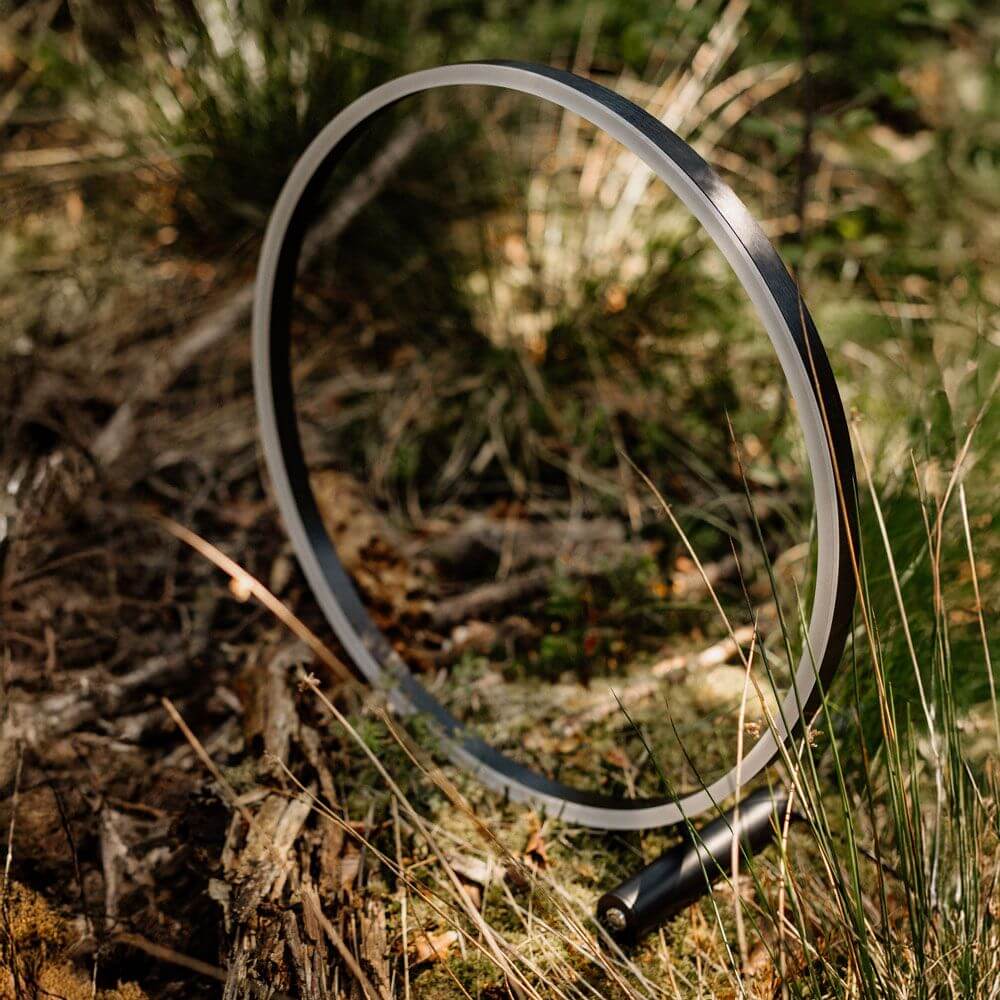 s.luce LED Ring Tischleuchte Direkt oder Indirekt im Freien auf grünem Untergrund zwischen Pflanzen.