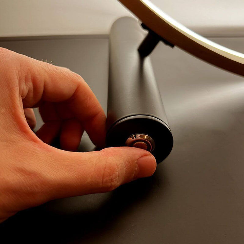 s.luce Lámpara de mesa LED Ring Directa o Indirecta: primer plano del ajuste con la mano en la base.