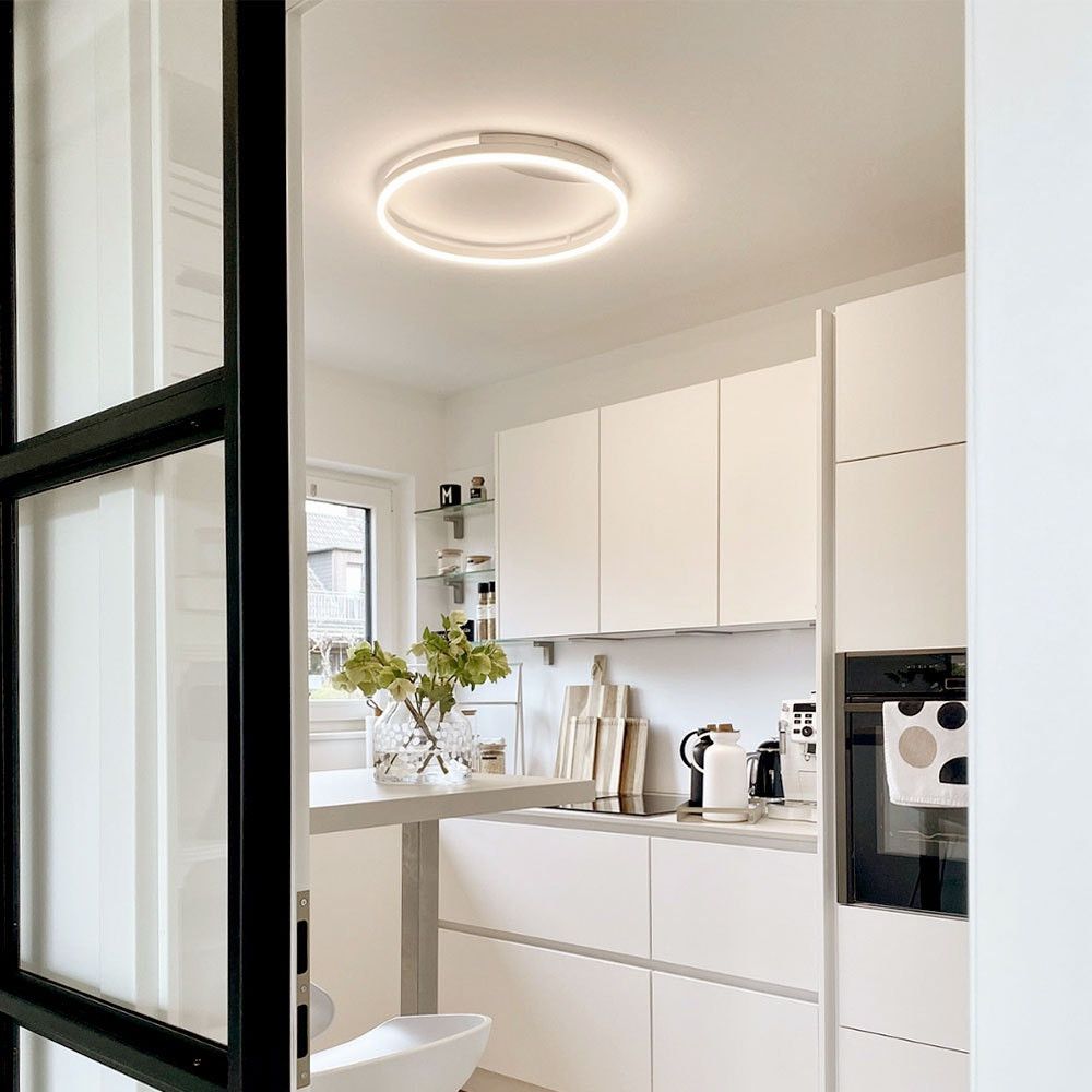 s.luce LED Aplique de parede e candeeiro de teto Ring Regulável moderno redondo numa cozinha moderna branca.