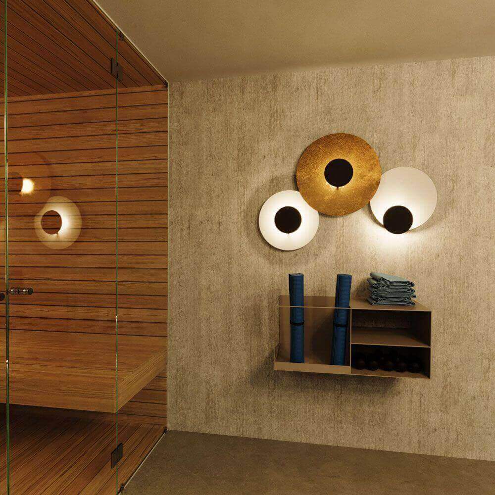 Modern Sauna-Bereich mit Holzverkleidung, dekorativen Wandleuchten und ordentlich gestapelten Handtüchern.