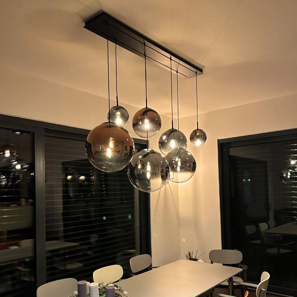 s.luce Módulo de viga con dosel y múltiples luces esféricas brillantes sobre una mesa de comedor.