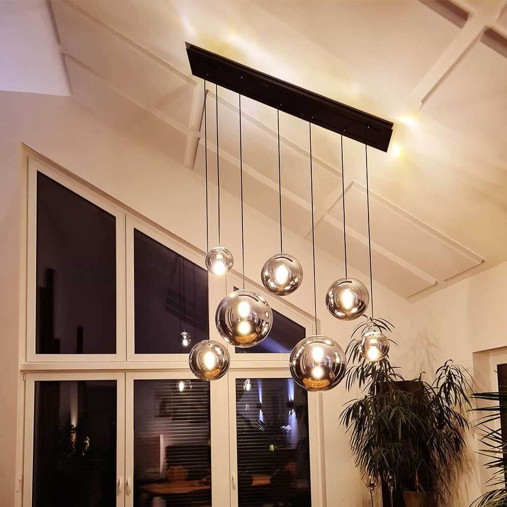 s.luce Orb 5-flammige Esstischlampe 2-reihig 160cm in modernem Wohnzimmer mit eleganten Glaskugeln.