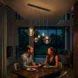 s.luce Orb Esstisch-Hängeleuchte 5-flammig 160cm über einem romantischen Dinner-Tisch bei Abendbeleuchtung.